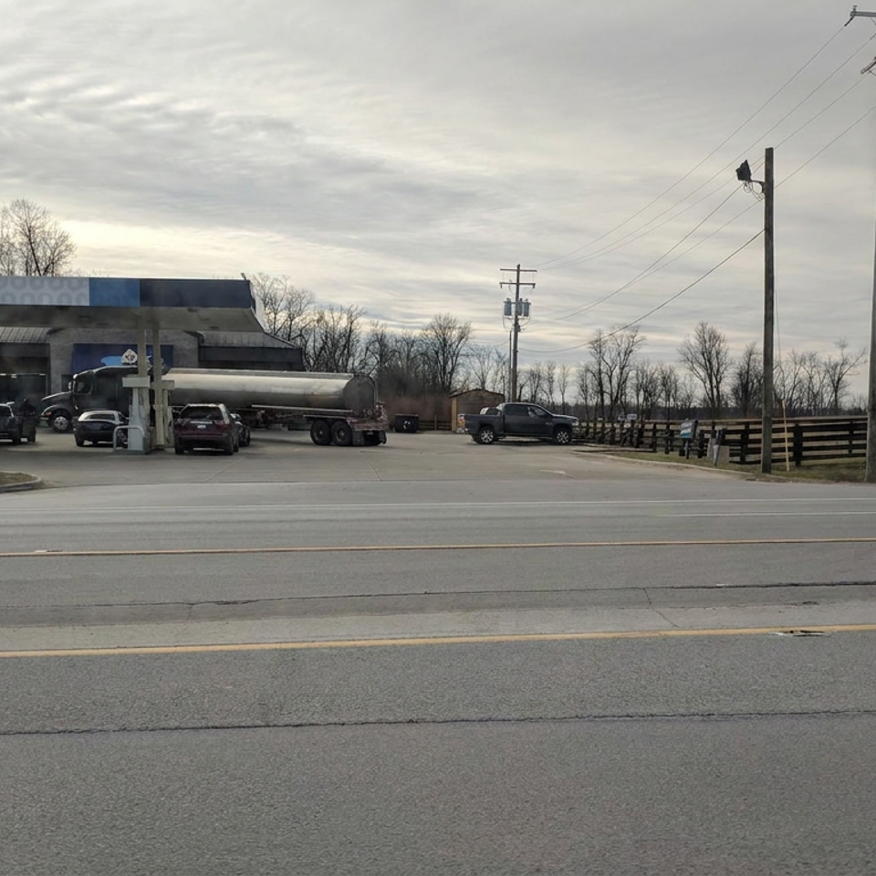 DoughDaddy’s gas station with vehicles and a fuel tanker beside a road under an overcast sky.